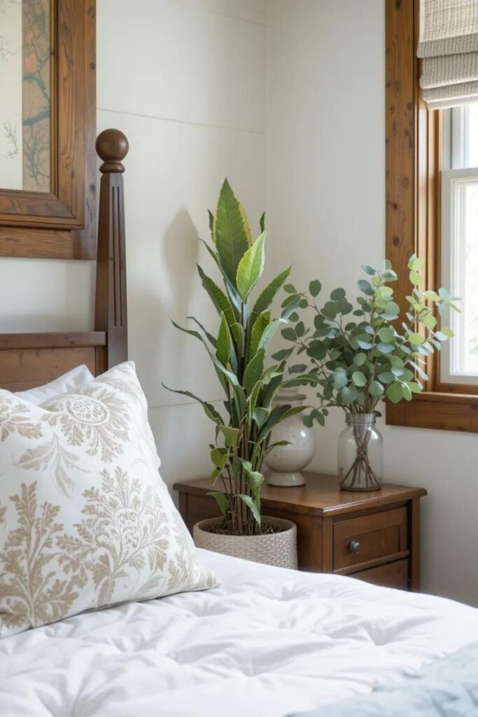 Farmhouse bedroom with a snake plant in a ceramic pot and eucalyptus in a glass jar.